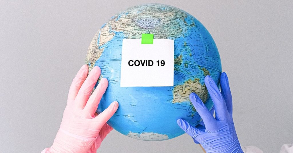 A globe with a piece of paper saying "Covid-19" stuck to it.