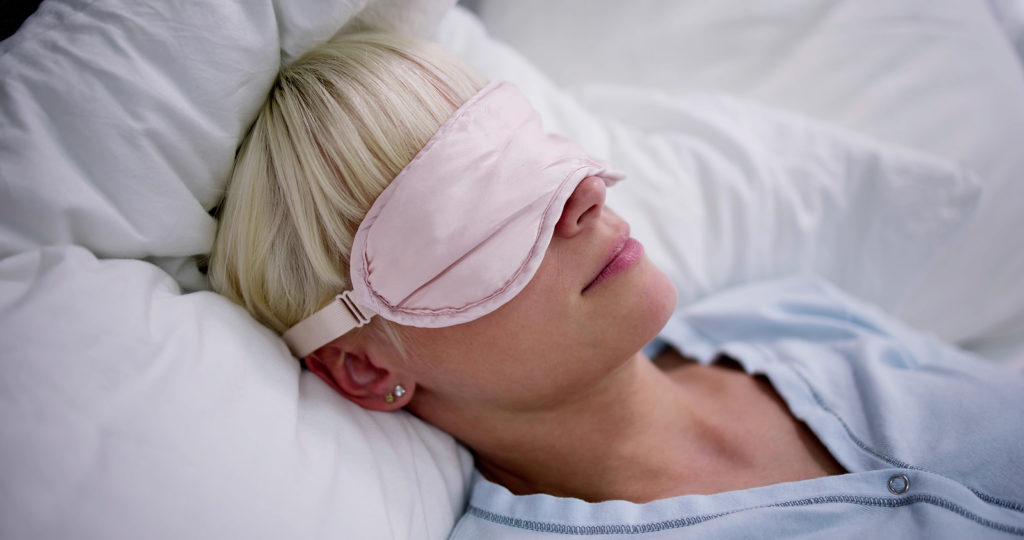 Young Woman Sleeping With Sleep Mask In Bedroom